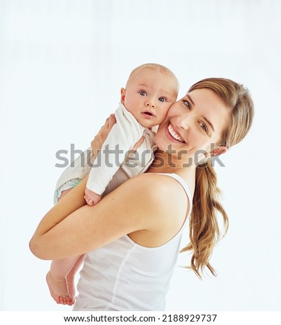 Portrait of a happy young mother hugging her cute baby boy at home, bonding and enjoying parenthood. Single parent being playful and affectionate, embracing precious moments with her new born child Royalty-Free Stock Photo #2188929737