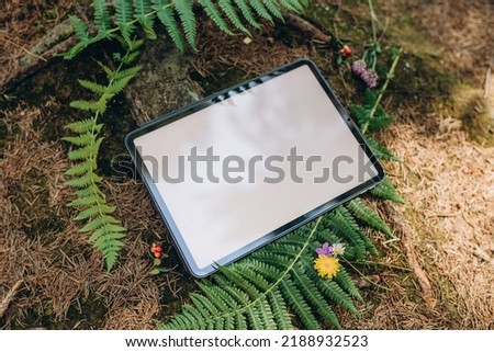 Tablet mockup on the background of nature in the forest. Workplace in nature, ipad mockup with blank white screen