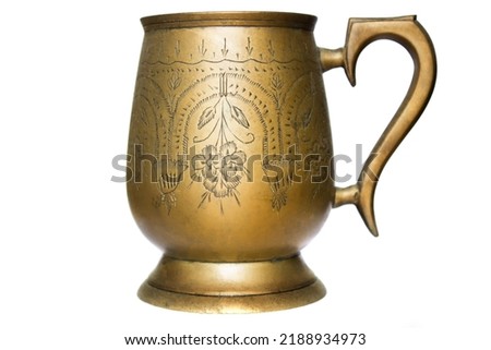 Copper mug with a pattern on a white background. Antique metal brass utensils. Museum exhibit item of utensils of kings.