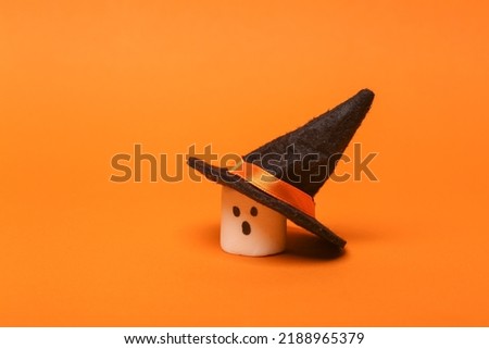 Halloween marshmallow with witch hat on orange background. Trick or Treat