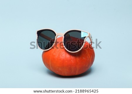 Pumpkin with sunglasses on a blue background Royalty-Free Stock Photo #2188965425