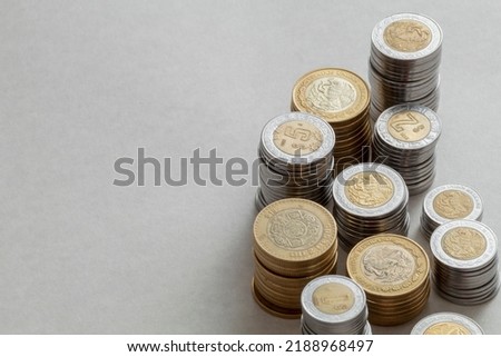 Mexican peso coins of different denominations stacked on a table with copy space.