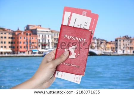 Woman holding international passport with boarding passes and beautiful view of city near sea on background