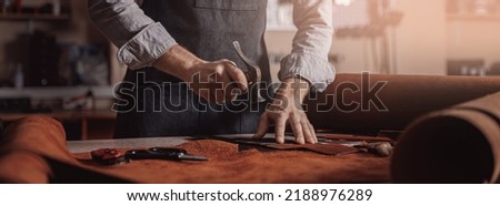 Tailor processing hammers seam on leather goods, Handmade craftsman. Royalty-Free Stock Photo #2188976289