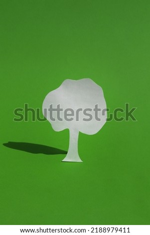 Paper tree on a green background. Tree with hard shadows. The concept of saving trees, fires in the forest