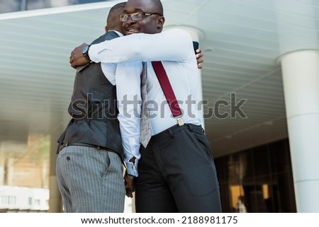 Greeting and handshake of two afro american businessmen partner against the backdrop of a modern building exterior. Friendly meeting outdoors