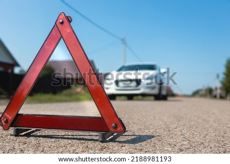 Car breakdown concept. Warning stop triangle close-up on the background of the car