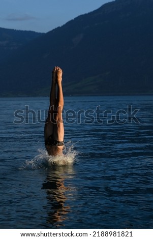 young european diver performs an element of jump on the shore of a lake in a mountainous area. Moment sportsman enter in the water