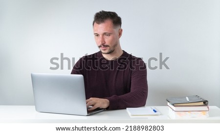 Concentrated work, a man works at a laptop at an office desk. High quality photo