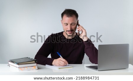 A man works in an office with a laptop, documents and talks on the phone. High quality photo
