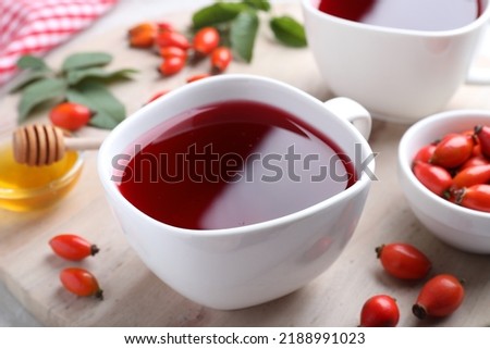 Fresh rose hip tea and berries on wooden tray, closeup