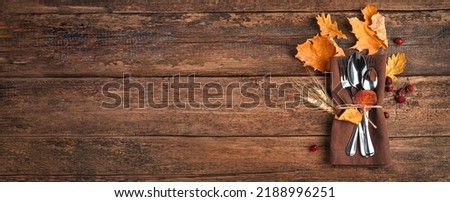 Napkin, cutlery and autumn leaves on a wooden background with space to copy. The concept of Thanksgiving, Halloween Royalty-Free Stock Photo #2188996251