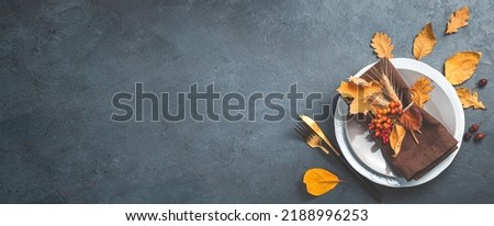 Autumn background with a plate with cutlery on a graphite background. The concept of Halloween, Thanksgiving. Top view, copy space