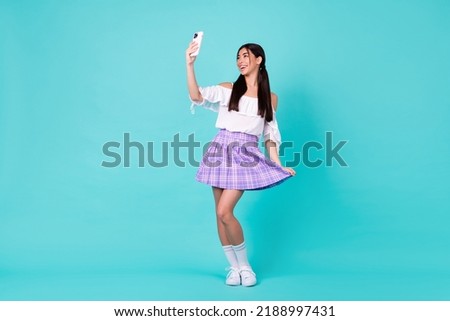 Full body portrait of gorgeous cheerful malaysian girl hold telephone make selfie touch skirt isolated on teal color background