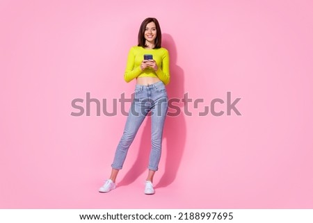 Full length photo of sweet shiny lady wear yellow top typing modern gadget walking isolated pink color background