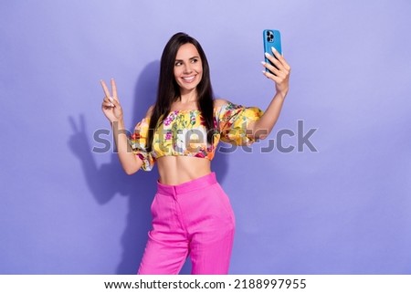 Portrait of lovely girl hold telephone make selfie demonstrate v-sign isolated on purple color background
