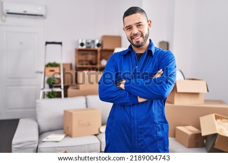 Young latin man worker smiling confident standing with arms crossed gesture at new home Royalty-Free Stock Photo #2189004743