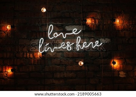 love lives here neon sign on brick wall