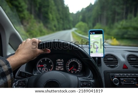 A man is driving on a gps navigator in a mountainous area, a view from inside the car.