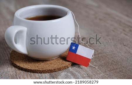 Tea in mug with Chile flag tea bag label. Wooden background.