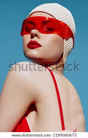 A close portrait of a lady in stylish trendy red glasses and a swimming cap looks down from over her shoulder. Fashion art concept Royalty-Free Stock Photo #2189060673
