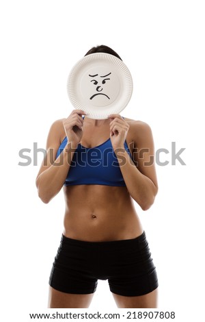 woman wearing sport bra and shorts holding a paper plate with a sad face draw on the plate over her face
