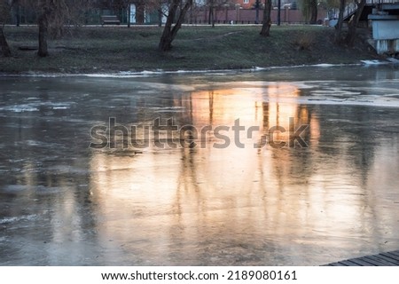 Reflection of orange sunset and trees in ice of frozen river in winter, abstraction Royalty-Free Stock Photo #2189080161