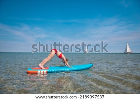 Sporty teen girl practising yoga and on sup or paddle board
