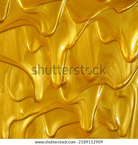 Glittering shiny metallic gold paint flowing and dripping downward making a golden background. Royalty-Free Stock Photo #2189112909