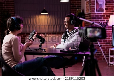 Man and woman recording podcast conversation on camera, vlogging discussion for social media content. Lifestyle blogger and female guest filming live broadcast stream on channel.