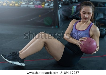 Asian sportswoman practicing Abs workout - fitness athlete working out doing strength training crunch oblique muscles with a ball. Fitness and sport and healthy concept. Royalty-Free Stock Photo #2189119937