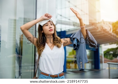 Angry female having sunstroke skin damage from sun UV city air pollution outside on street, Overheating Asian beautiful business woman drying sweat her face with cloth in warm summer day hot weather Royalty-Free Stock Photo #2189147735