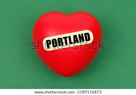 Love for the city, homeland. On a green surface lies a red heart with the inscription - Portland