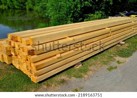 Planed boards are stored on the river bank on a summer day