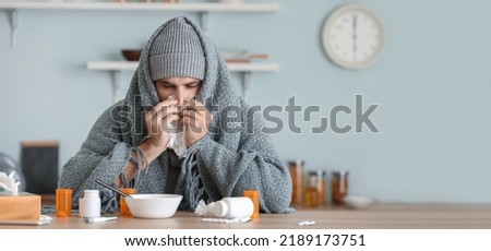 Sick man sitting at kitchen table Royalty-Free Stock Photo #2189173751