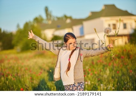 A school-age girl in a clearing with poppies. Spring leisure in nature.