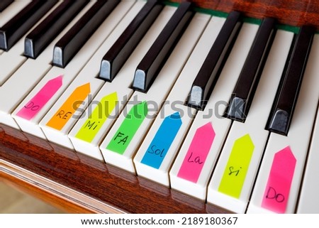 Piano keys are covered with multi-colored stickers with the designation of notes