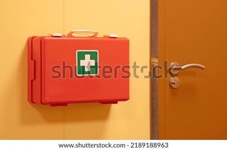 Orange first aid case hanging on the wall for safety measures