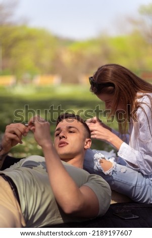 Unique perspective of two teenage friends taking picture with smartphone while lying down on green meadow