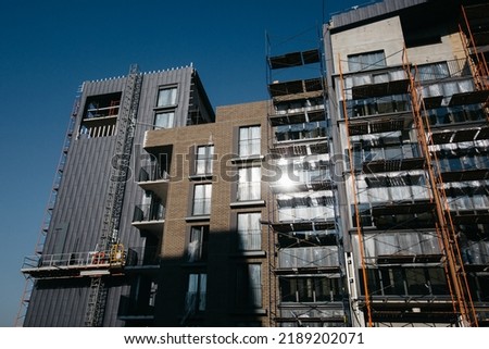 Suspended construction craddle near wall of hightower residentaial building with insulation and ventilated facade on construction site. Engineering urban background. High quality photo