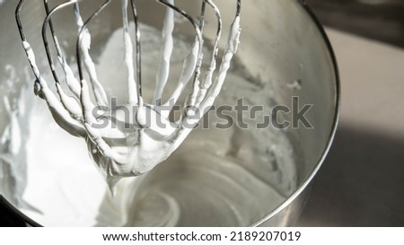 Mixing Whipped Cream in a Stand Mixer with a Whisk Attachment: Heavy whipping cream mixed with a stand mixer wire whisk Royalty-Free Stock Photo #2189207019