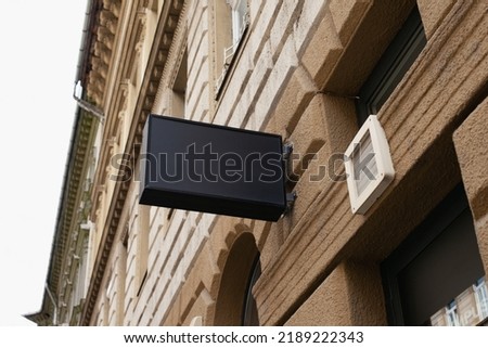 Shop sign building mockup. Black rectangular color store mockup for your logo. Minimalist style in modern city.