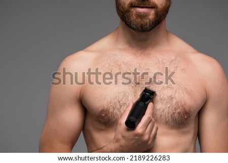 cropped view of shirtless man shaving hair on chest with electric razor isolated on grey Royalty-Free Stock Photo #2189226283