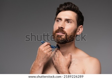 shirtless man shaving beard with safety razor isolated on grey
