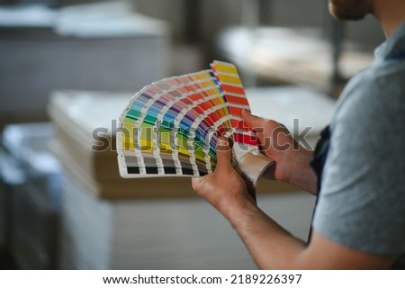 Man working in printing house with paper and paints.