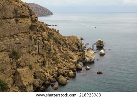 Seascape color landscape photo. Mountain sea shore with yellow hills and capes cliffs. Calm sea and blue sky with white clouds. It is photographed in the fall in cloudy day.