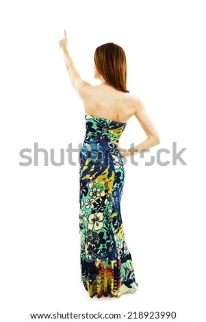Beautiful girl in the summer dress pointing at wall. Rear view. Isolated on white background 