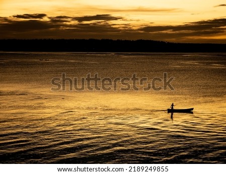 Fisherman in his small barge moving in the Guarairas lagoon in Tibau do sul during sunset.