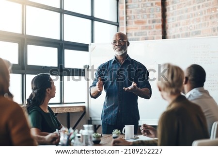 Senior business man doing presentation, planning and talking in a meeting, seminar or training workshop in a boardroom. Manager sharing ideas, teaching and coaching new employees during conference Royalty-Free Stock Photo #2189252227