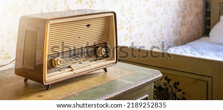 Old retro vintage radio on a aged wooden table illuminated by the sun - Aged bedroom or hotel room